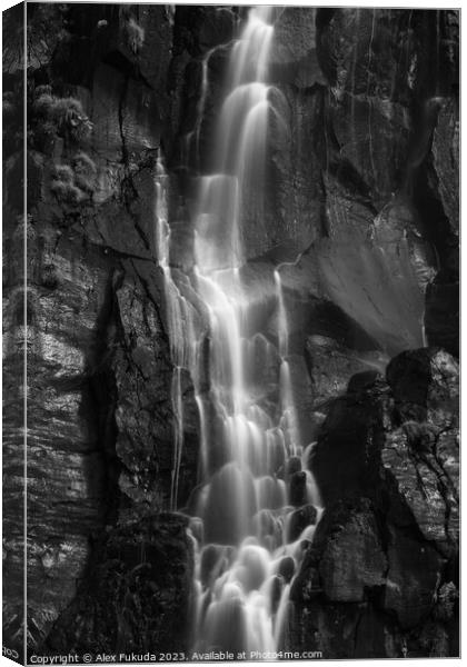 A waterfall cascading down black rock cliff Canvas Print by Alex Fukuda