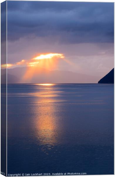 A sunburst over a Norwegian fjord Canvas Print by Iain Lockhart