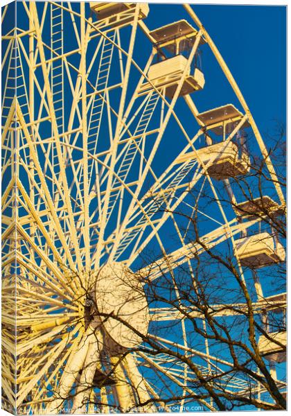 Ferris wheel against a clear blue sky with sunlight casting shadows, conveying a sense of leisure and entertainment in Lancaster. Canvas Print by Man And Life