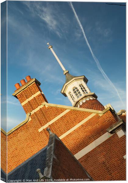 Historic brick building with a distinctive cupola against a blue sky with contrails. Canvas Print by Man And Life