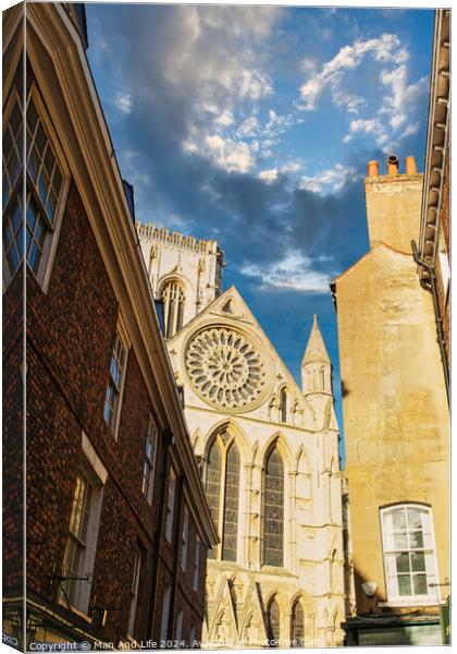 Historic cathedral facade with rose window, framed by old buildings against a blue sky with clouds in York, UK. Canvas Print by Man And Life