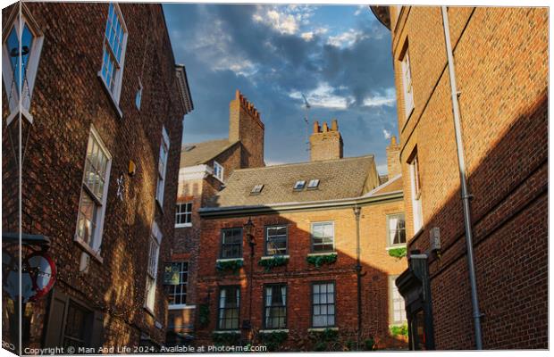 Charming European alleyway with historic brick buildings and a glimpse of blue sky with clouds in York, UK. Canvas Print by Man And Life