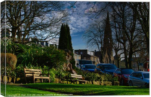 Tranquil urban park scene with benches and lush greenery, set against a backdrop of historic buildings and blue sky with wispy clouds in Harrogate, England. Canvas Print by Man And Life