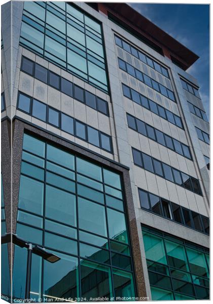 Modern office building facade with reflective glass windows against a blue sky in Leeds, UK. Canvas Print by Man And Life