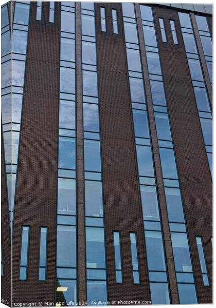 Modern building facade with a pattern of windows and brickwork against a blue sky in Leeds, UK. Canvas Print by Man And Life