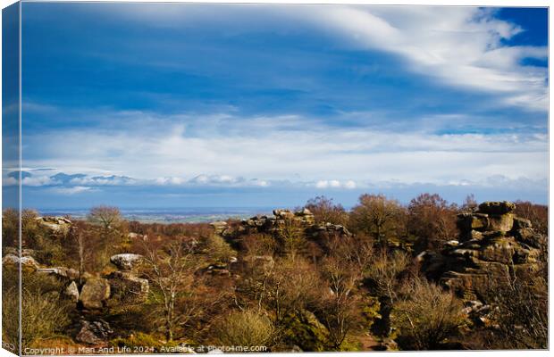 Scenic view of rocky terrain with lush greenery under a blue sky with fluffy clouds, overlooking a distant body of water at Brimham Rocks, in North Yorkshire Canvas Print by Man And Life