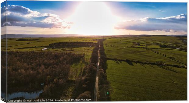 Aerial view of a scenic country road at sunset with lush green fields and a dramatic sky in North Yorkshire. Canvas Print by Man And Life