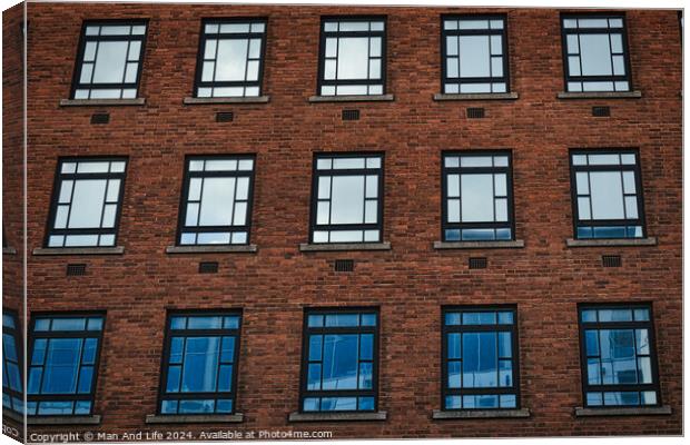 Facade of a brick building with symmetrical windows reflecting the sky in Leeds, UK. Canvas Print by Man And Life