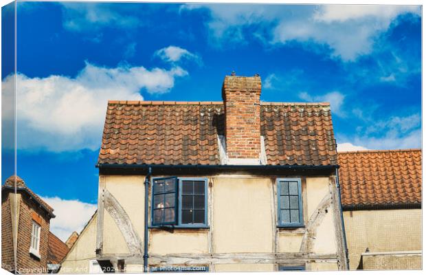 Old European building with weathered facade and terracotta roof tiles against a backdrop of a vibrant blue sky with fluffy clouds in York, North Yorkshire, England. Canvas Print by Man And Life