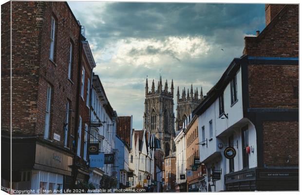 Quaint European street leading to a majestic Gothic cathedral under a dramatic sky at dusk, showcasing historical architecture and urban charm in York, North Yorkshire, England. Canvas Print by Man And Life