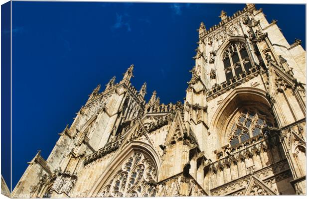 Gothic cathedral facade against a clear blue sky, showcasing intricate architectural details and stone carvings, perfect for historical and travel themes in York, North Yorkshire, England. Canvas Print by Man And Life