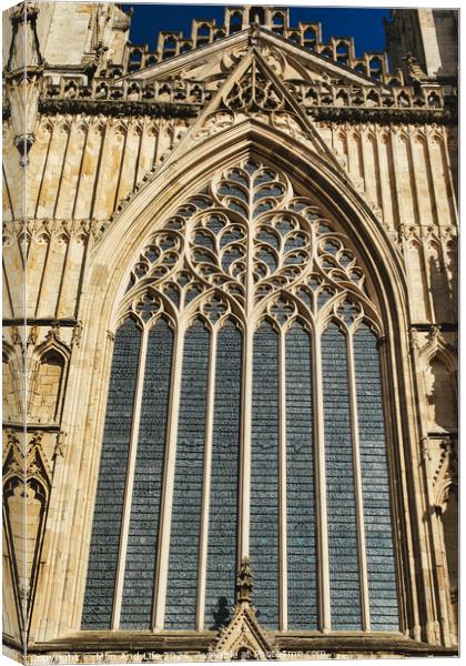 Gothic architecture detail of a cathedral window with intricate tracery and stained glass, set against a clear blue sky in York, North Yorkshire, England. Canvas Print by Man And Life