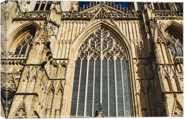 Gothic architecture detail of a cathedral's facade, featuring a large stained glass window and ornate stone carvings under clear skies in York, North Yorkshire, England. Canvas Print by Man And Life