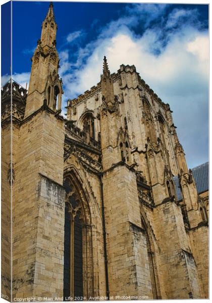 Gothic cathedral facade against a blue sky with clouds. The image captures the intricate architecture and towering spires of the historic religious building in York, North Yorkshire, England. Canvas Print by Man And Life