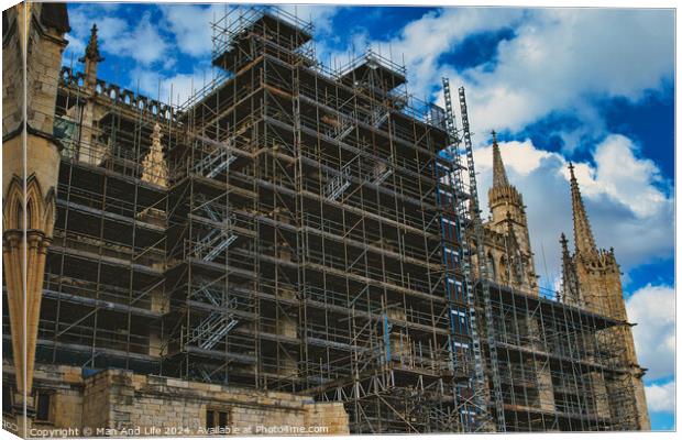 Gothic cathedral undergoing restoration, with extensive scaffolding against a dramatic cloudy sky in York, North Yorkshire, England. Canvas Print by Man And Life