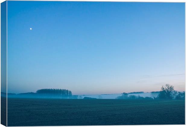 Moon over mist covered rural scene. Canvas Print by Liam Grant