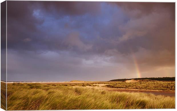 Storm clouds and rainbow at sunset. Holkham, Norfo Canvas Print by Liam Grant