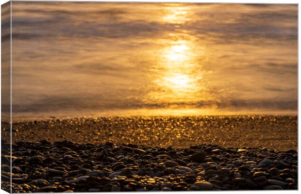 Golden sunlight on sea and pebble beach Canvas Print by Phil Crean