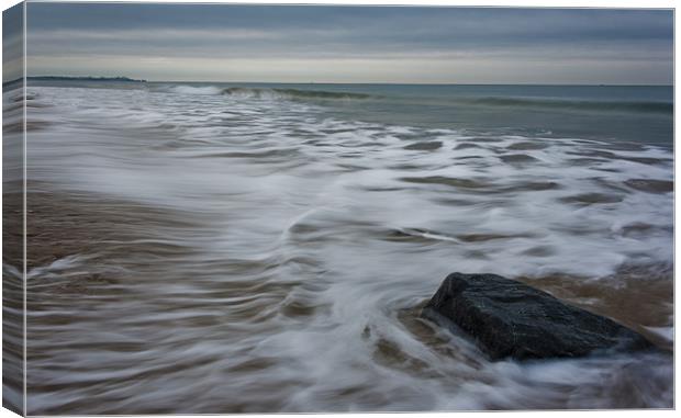 Ebb tide and a rock Canvas Print by Ian Jones