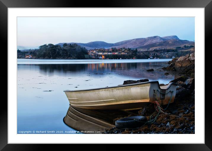 A dinghy moored at the loch's edge with reflected view of Portree  Framed Mounted Print by Richard Smith