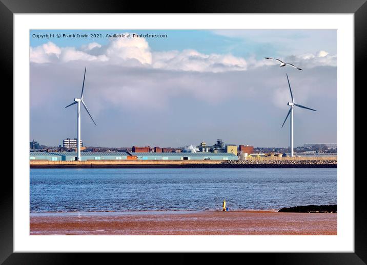 A lone fisherman dwarfed by two "on-shore wind tur Framed Mounted Print by Frank Irwin