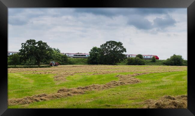 A Virgin train passes a tractor on a field Framed Print by Jason Wells
