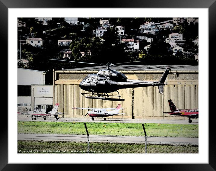 Helicopter hovering with planes in the background Framed Mounted Print by Ann Biddlecombe
