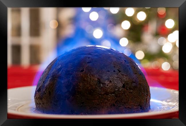 Christmas Pudding on a table, with a Christmas tre Framed Print by Dave Carroll