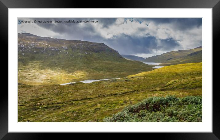 A lush green hillside with three lochs in the back Framed Mounted Print by Marcia Reay