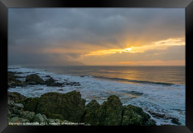 A rocky beach next to a body of water Framed Print by Paul Collis