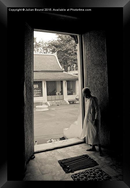 A nun in a doorway of a temple in Bangkok, Thailan Framed Print by Julian Bound