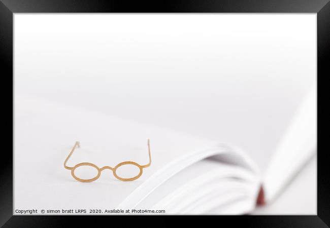 Tiny reading glasses on open book Framed Print by Simon Bratt LRPS