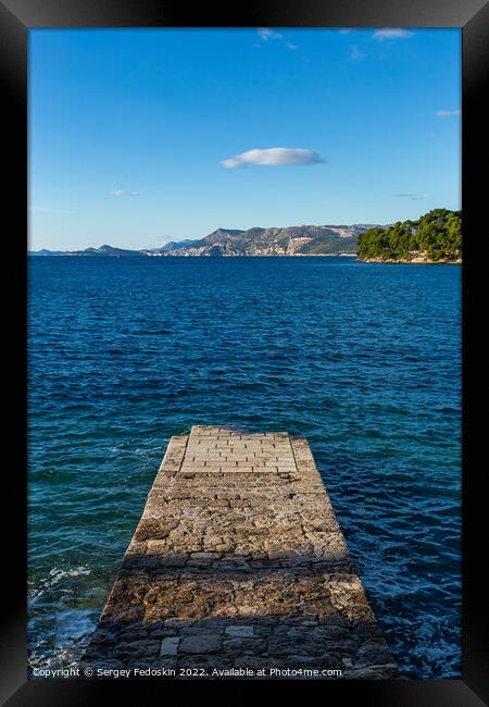 Stone pier in the sea with mountains in the background Framed Print by Sergey Fedoskin