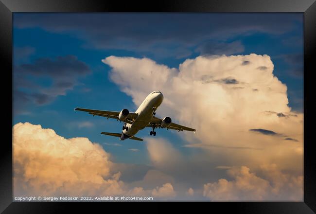 Passenger commercial aircraft flying on a dramatic sky background. Framed Print by Sergey Fedoskin