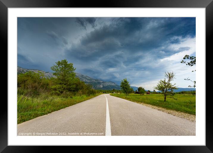 Empty countryside road in valley. Landscape with dramatic sky. A storm is coming from the mountains. Framed Mounted Print by Sergey Fedoskin