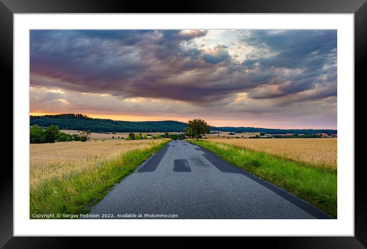 Road in rye fields. Summer evening. Sunset sky. Framed Mounted Print by Sergey Fedoskin