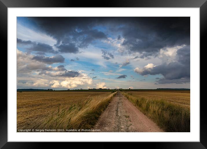 Dramatic storm clouds over fields. Country landscape. Windy weather. Plain field against the background of dark sky. Framed Mounted Print by Sergey Fedoskin