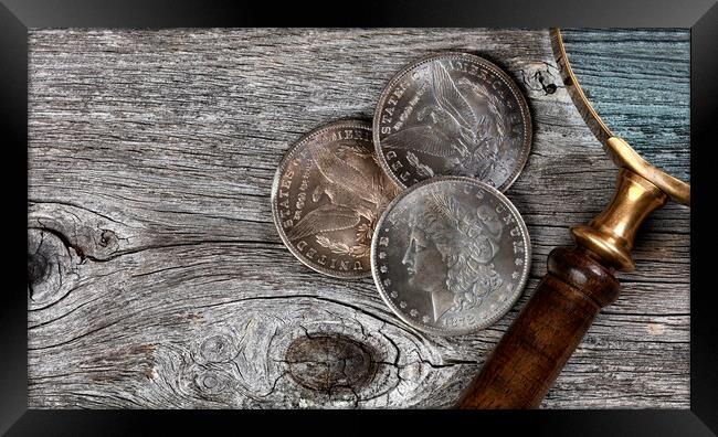 Collection of US Morgan silver dollars with magnifying glass  Framed Print by Thomas Baker