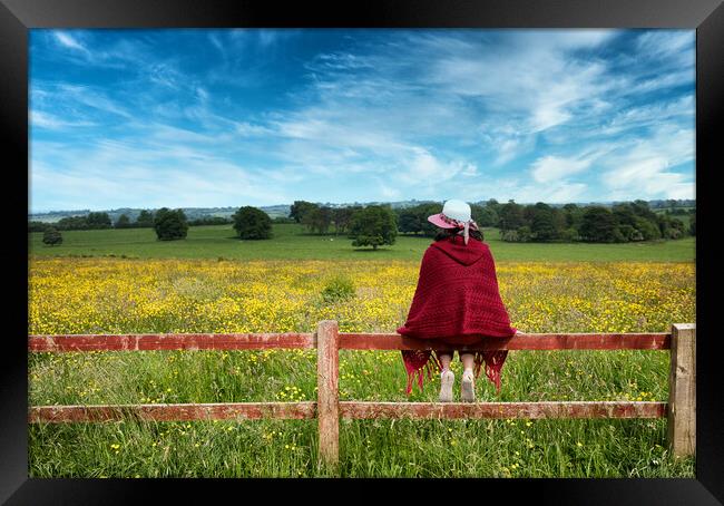 Woman sitting on fence while looking out at the farmland   Framed Print by Thomas Baker