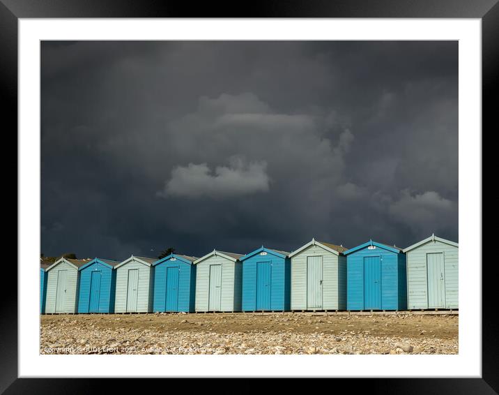 Blue beach huts under a black sky Framed Mounted Print by JUDI LION