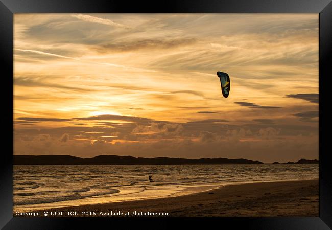 Kite surfer riding along the tideline at sunset Framed Print by JUDI LION