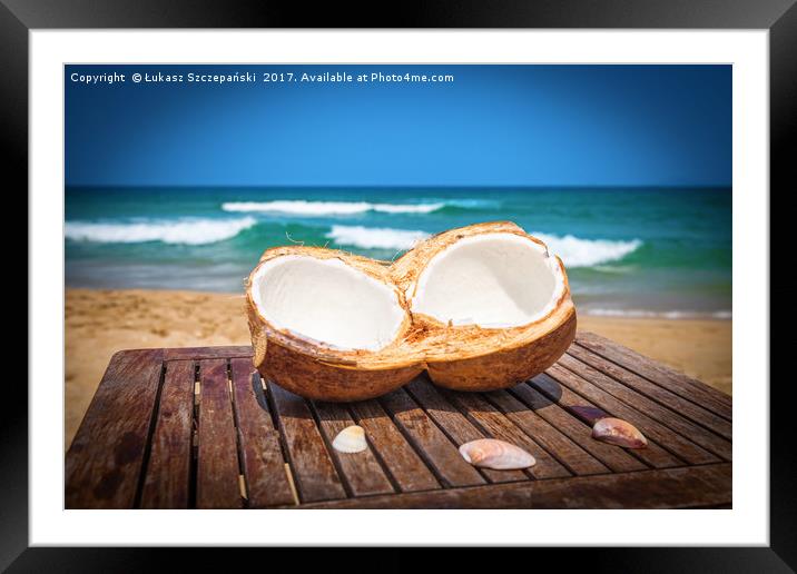 Coconut on the table against beautiful beach Framed Mounted Print by Łukasz Szczepański
