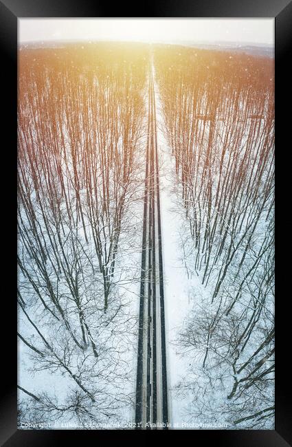 Road through winter forest towards setting sun Framed Print by Łukasz Szczepański