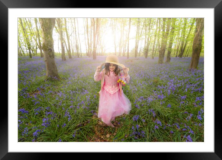 Small girl walks through bluebell woods in pink dress Framed Mounted Print by Alan Hill