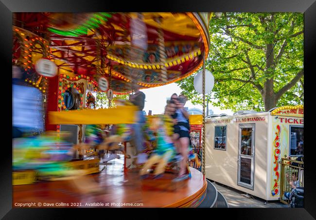 Fairground carousel ride blurred to show speed and movement with small child watching, London UK Framed Print by Dave Collins