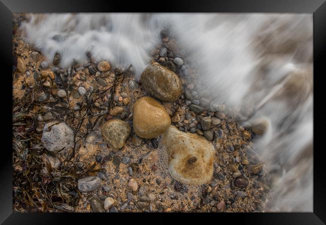 Pebbles being washed over by the incoming tide. Framed Print by Bryn Morgan