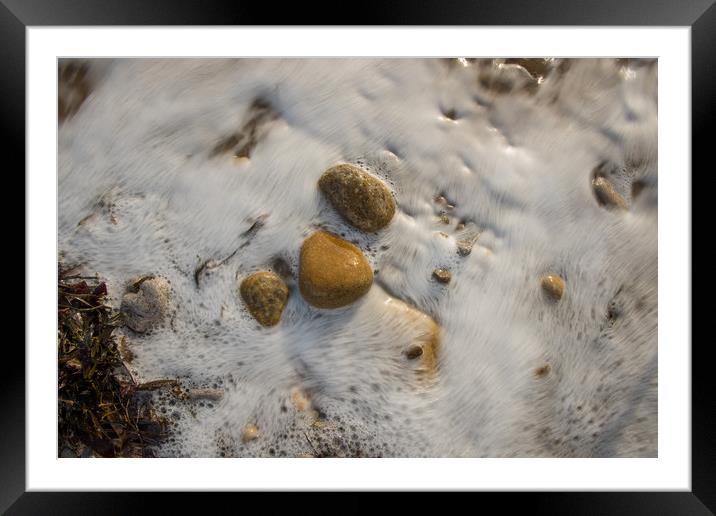 Pebbles being washed over by the incoming tide. Framed Mounted Print by Bryn Morgan