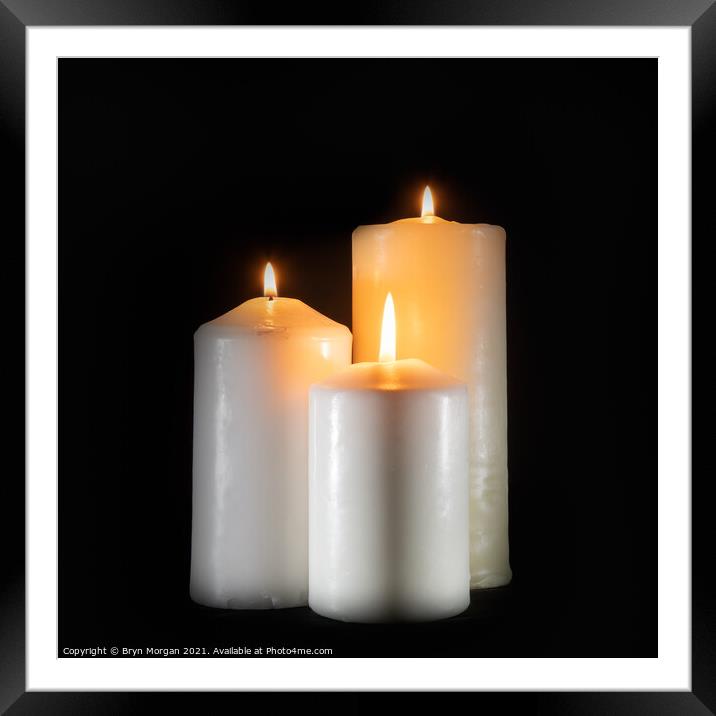 Three burning candles in the darkness Framed Mounted Print by Bryn Morgan