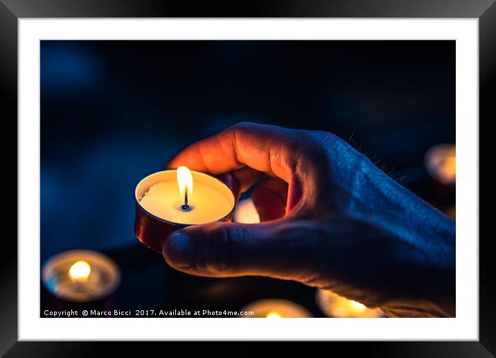 A hand of a man holds a candle in a church Framed Mounted Print by Marco Bicci