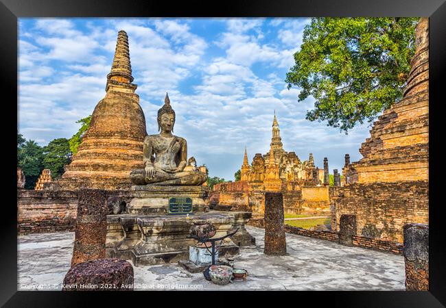 Buddha statue with Wat Mahathat in the background Framed Print by Kevin Hellon